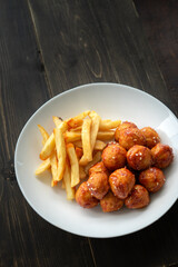 Spicy coated meatballs with spicy sauce served with fried potatoe fries. Korean style snacking.