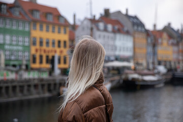 Close-up of a girl's head from behind looking at the colorful houses at Nyhavn in Copenhagen,...