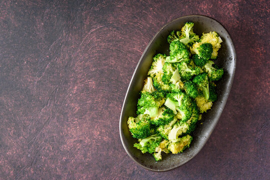 Serving dish of fresh roasted broccoli florets on a rustic background
