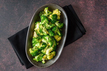 Serving dish of fresh roasted broccoli florets on a rustic background
