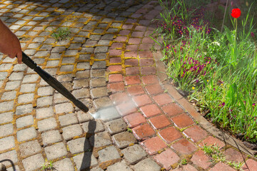 Cleaning street with high pressure power washer, washing stone garden paths