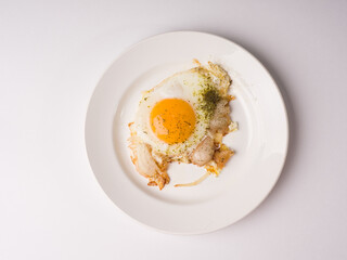 Fried eggs on a white round plate. Studio photo on white background