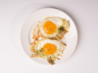 Fried eggs on a white round plate. Studio photo on white background