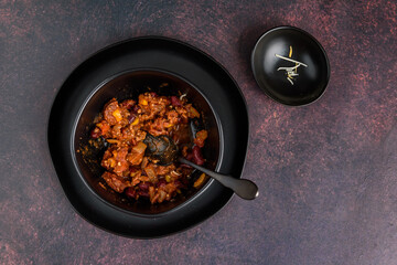 Black bowl of spicy chili con carne on a rustic moody background
