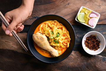 Northern Thai food (Khao Soi), Spicy curry noodles soup with chicken eating with crispy deep-fried egg noodles, pickled mustard, shallots, lime and ground chilies in oil