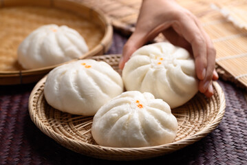 Obraz na płótnie Canvas Steamed buns stuffed with minced pork holding by hand, Asian food