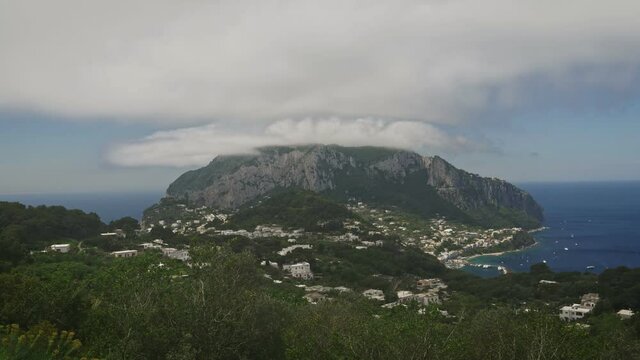 Aerial timelapse of the island of Capri with clouds that pass trough the top of the island.
