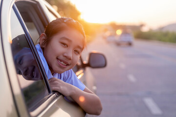Asian little girl looking something out the car. In the morning, the girl was looking at something outside the car window on the way to school. children relax with street view from the car. 