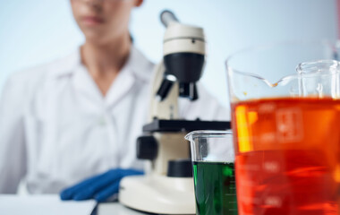 Fototapeta premium woman doctor in a medical gown and a microscope on the table glasses on the face laboratory research