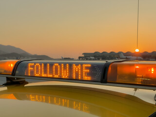 "follow me" light bar on airfield vehicle with sunset background