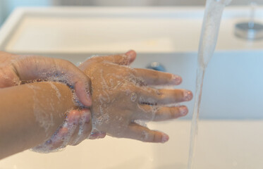 Fototapeta premium Prevent coronavirus or COVID-19 concept. Handwashing of hand and wrist wash with bubble soap at sink.