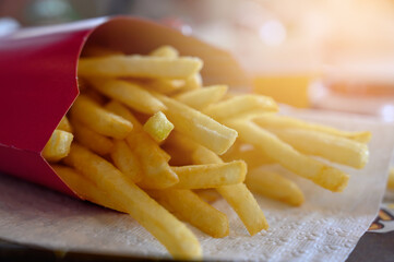 french fries in red paper bag on white paper. Potatoes fries in fast food restaurant