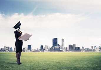 Camera headed woman standing on green grass against modern cityscape