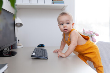 Caucasian funny little baby boy exploring computer, monitor and keyboard