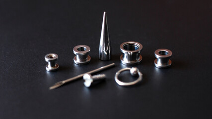 Set for piercing on a dark background, ear tunnels, tunnels and earrings for the ears and tongue closeup