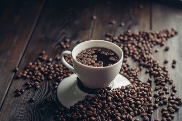 a cup of hot coffee on a wooden table and sprinkled beans close-up