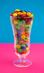 Glass Filled with Rainbow Colored Candy Coated Chocolate Buttons