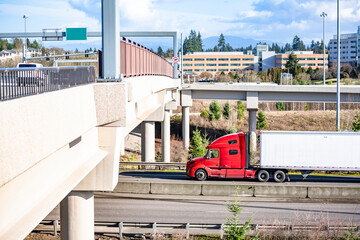 Bright red big red semi truck with dry van semi trailer running on the highway intersection with...