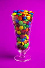 Glass Filled with Rainbow Colored Candy Coated Chocolate Buttons