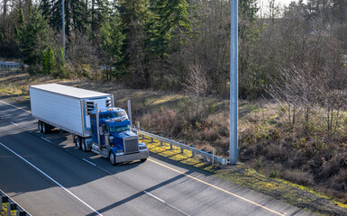 Classic blue big rig semi truck tractor with chrome accessories transporting frozen cargo in...