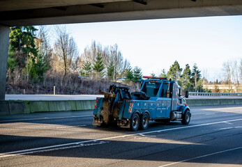 Powerful blue big rig tow semi truck with boom and other towing equipment