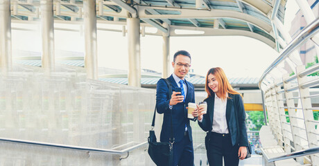 Banner Businessman Businesswoman drinking coffee in town using smartphone outside office city. Panorama Hands holding take away coffee cup, smart phone talking together Business partner copyspace