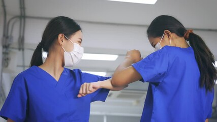 Young female healthcare workers wearing surgical mask shaking hands with elbow bump while maintaining social distancing during the outbreak of corona virus pandemic - 4k slow motion footage