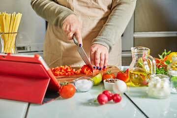 Woman cooking according the tutorial of online virtual master class, And looking on the digital...