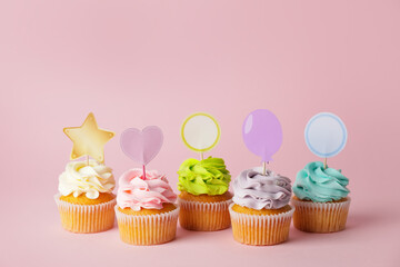 Tasty cupcakes with stylish toppers on color background