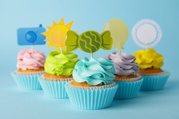 Tasty cupcakes with stylish toppers on color background