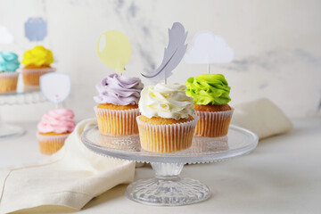 Tasty cupcakes with stylish toppers on light background