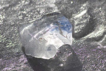 Frozen shiny ice cube melting in the sun with nice reflections in the transparent ice in arctic...