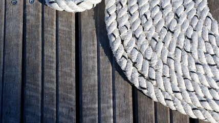 strong white nautical rope in a circle around a pier on the background of wooden boards