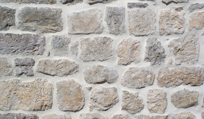 background of a solid gray stone wall of cement, limestone, sand and old multi-colored cobblestones with an uneven surface, of different sizes and shapes