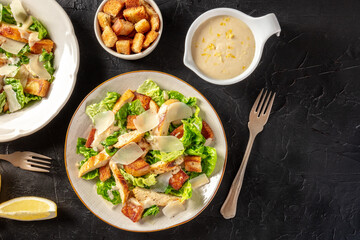 Chicken Caesar salad, shot from above with croutons and the classic dressing, on a black background with a place for text