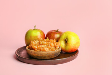Plate with sweet apple jam on color background
