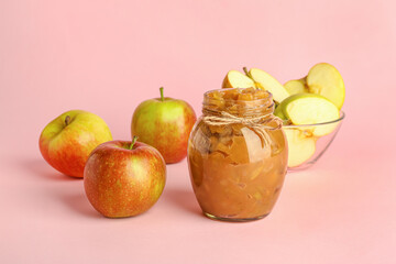 Jar with sweet apple jam on color background