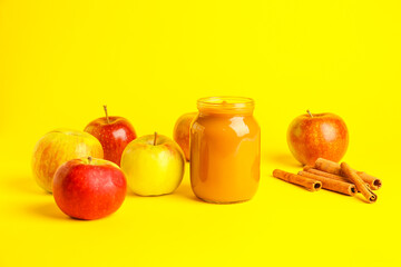 Jar with sweet apple jam on color background