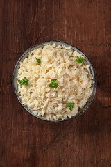 Rice, overhead shot on a rustic wooden table, with fresh parsley leaves and a place for text