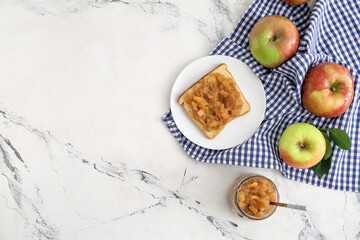 Jar and toast with sweet apple jam on light background