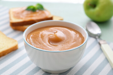 Bowl with sweet apple jam on color background