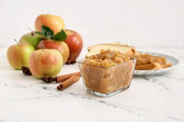 Bowl with sweet apple jam on light background
