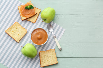 Bowl and toasts with sweet apple jam on color wooden background