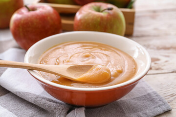 Bowl and spoon with sweet apple jam on wooden background