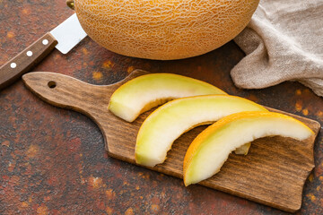 Board with sweet cut melon on grunge background