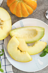 Plate with sweet cut melon on gray background