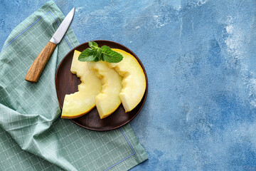 Plate with sweet cut melon on color background