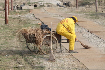 Lucknow, Uttar Pradesh India- February 09 2021: A sewage cleaner is loading the garbage collecting cart to keep the locality clean.