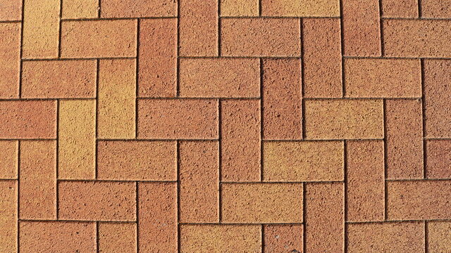 sandy brown natural stone in machined rectangular blocks laid out in pavement masonry, graphic resource of masonry in bright sunny detailed lighting view from the top angle full frame