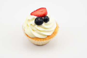 Pastry tartlet with custard, two blueberries and half strawberry isolated on white background